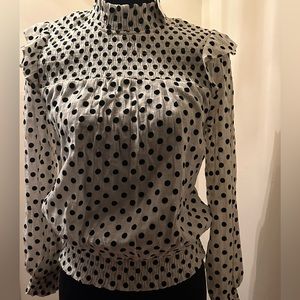Black and white polka dot blouse with ruffled shoulders.
